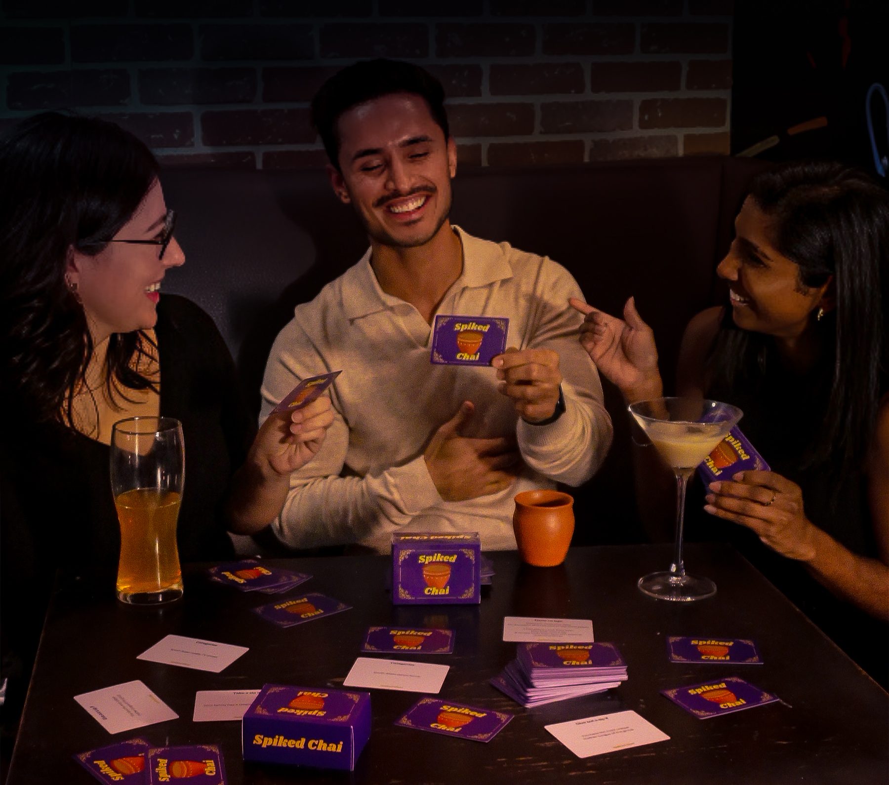 Friends playing Spiked Chai with drinks and cards on the table