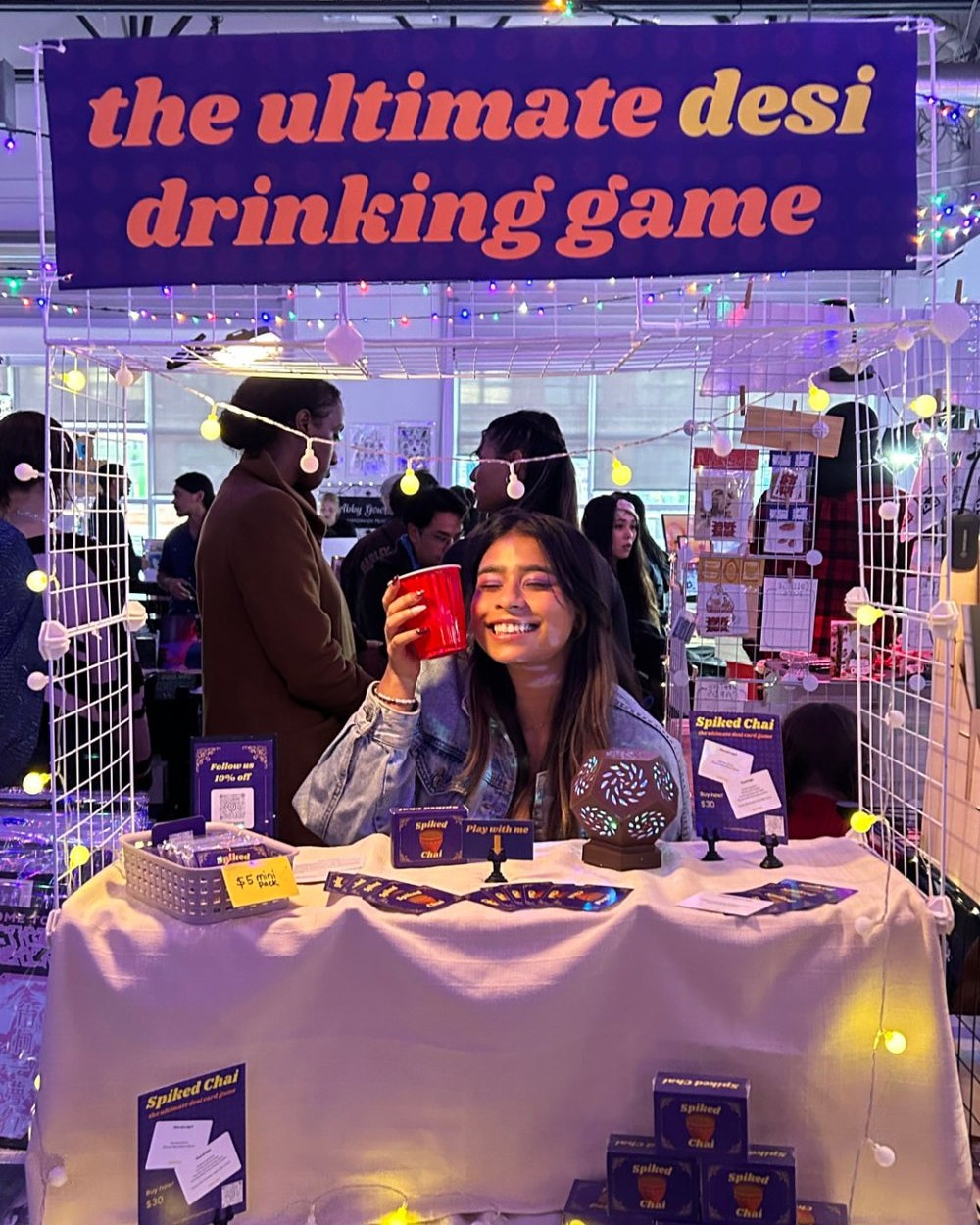 The Spiked Chai booth at a market, founder holding up a red party cup